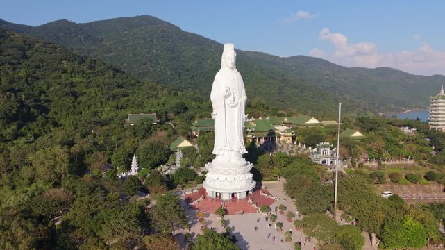 Drone Approach To Towering White Statue On Hilltop Shrine, Aerial Descent Revealing Courtyard, Pathways And Forested Slopes At Son Tra, Da Nang, Vietnam, Calm Discovery Mood