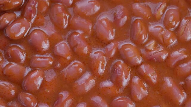 Glossy beans in rich sauce, Steaming red beans coated with savory rich tomato glaze, Macro shot of glossy cooked beans immersed in thick tomato gravy with warm tones