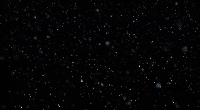 Static shot of white dust particles and snow flakes drifting against a black background with cinematic bokeh effects