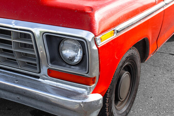 Classic red 1970s 1980s pickup truck vintage vehicle front detail old automobile chrome bumper headlight style outdoors transportation antique car bodywork bright paint metal grille close view © Tom Sanches