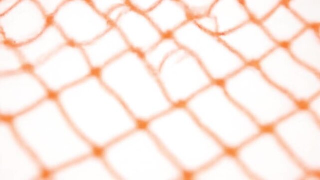 Orange plastic netting in abstract pattern with soft focus and white background for texture overlay
