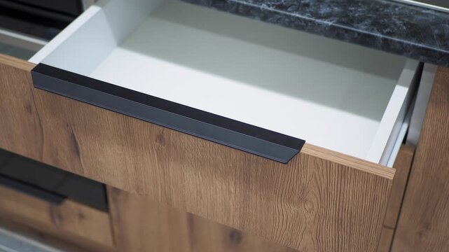 Modern kitchen drawer with wooden finish closing smoothly on high quality rails motion footage