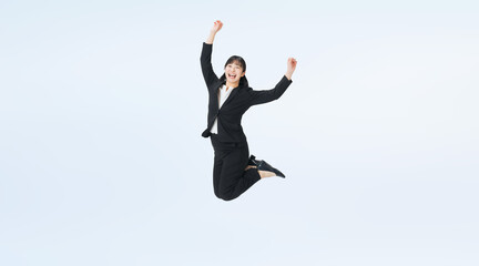 ジャンプするスーツの女性ビジネスパーソンの全身写真