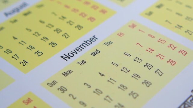 Close-up cinematic footage of calendar pages in motion, highlighting months and dates for time organization and event planning