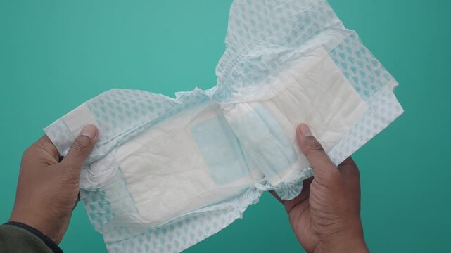 Holding absorbent pad with light blue design on turquoise background