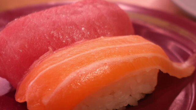 Fresh tuna and salmon nigiri sushi on red plate at Japanese restaurant
