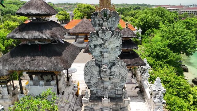 Extreme close-up aerial drone fly-in to traditional Garuda stone statue at Pura Geger temple, Bali, Indonesia