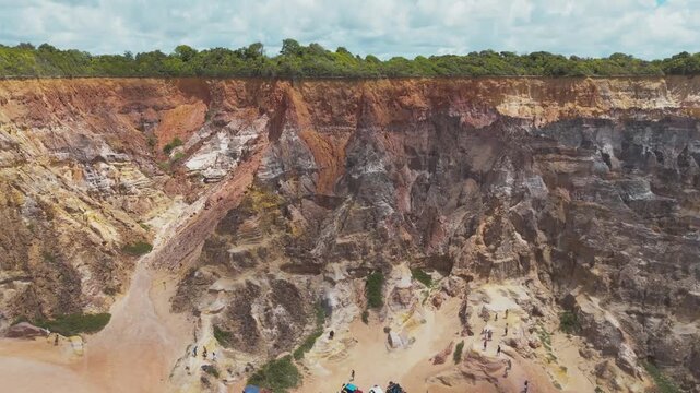Aerial drone video of a beach in Brazil, Alagoas state, on Gunga beach, near Maceio, giant cliffs next to the sea, buggies and tourists strolling in this paradisiacal place.