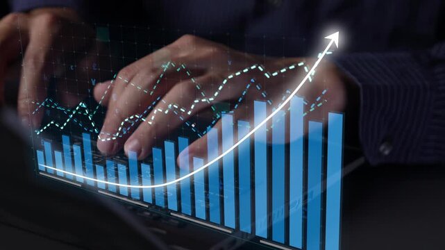 Close-up view of hands working on a keyboard while analyzing digital financial data on a screen, showcasing growth and valuable insights in a modern office setting. Copula