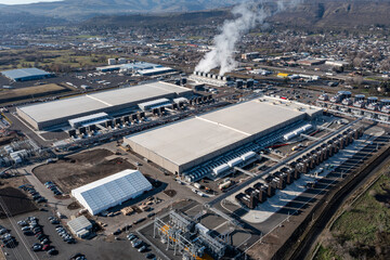 Aerial drone picture of a large data center campus with cooling steam, electrical substation along the Columbia River in The Dalles, Oregon, USA. Power demand for cloud computing AI infrastructure © Hrach