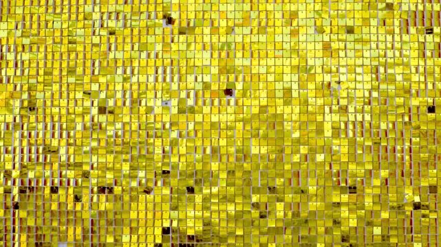 Tracking shot of reflective gold mosaic tiles shifting and shimmering across wall surface in close up interior decor