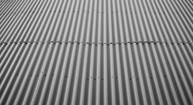 A close-up photo of a corrugated metal surface with a seamless pattern of parallel ridges and grooves