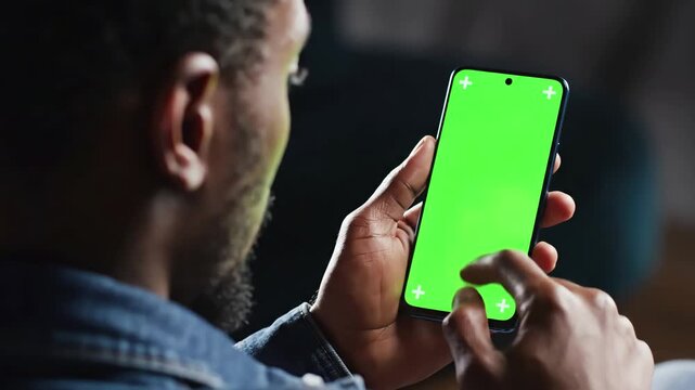 Green Screen close up shot of head and hand afro american man holding his smartphone with looking on it scrolling touching backside view mock scene 3 distortion, overlay, glitch, static noise, scan