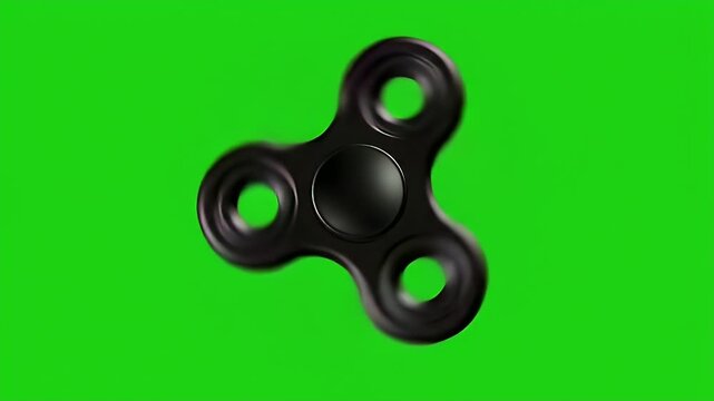 Black fidget spinner spinning rapidly against a bright green background