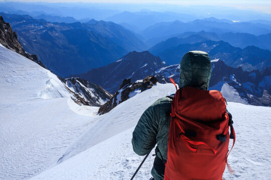 Mountaineer in rope team with crampons descending from summit Parrotspitze and mountain glacier panorama in summer in Pennine Alps, Italy