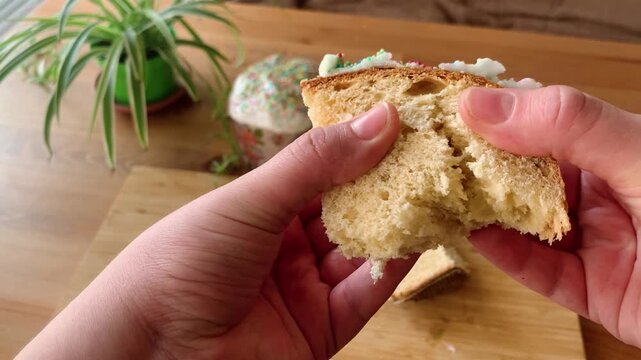Female hands breaking and cutting traditional Easter bread. Fresh homemade kulich with soft texture inside. Easter baking and festive pastry.
