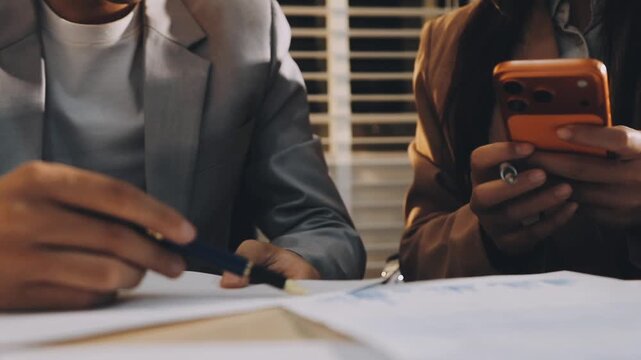 Accountant reviewing printed financial reports at messy office desk with calculator and sticky notes under soft window daylight for audit and corporate finance work