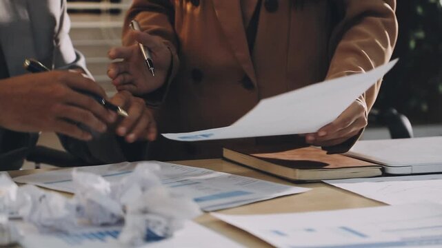 Accountant reviewing printed financial reports at messy office desk with calculator and sticky notes under soft window daylight for audit and corporate finance work