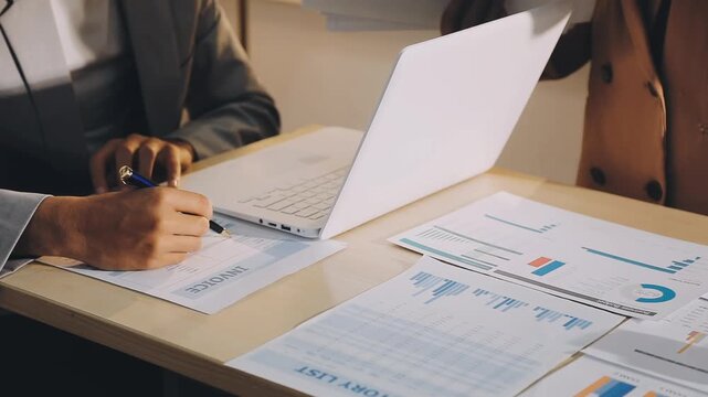 Accountant reviewing printed financial reports at messy office desk with calculator and sticky notes under soft window daylight for audit and corporate finance work