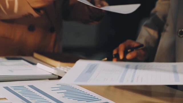 Accountant reviewing printed financial reports at messy office desk with calculator and sticky notes under soft window daylight for audit and corporate finance work