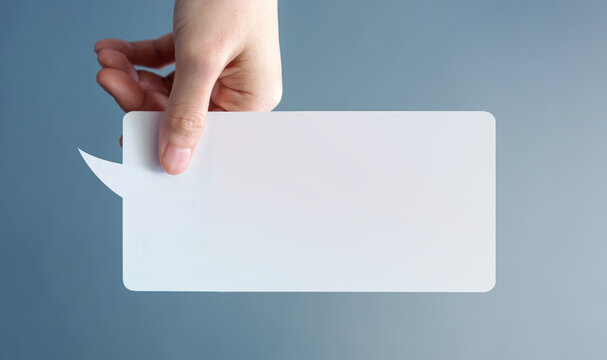 Hand holding blank Speech Bubble against blue background. Minimal concept of free speech