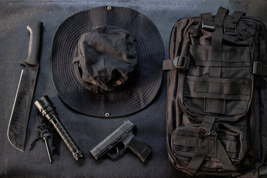 Hiking equipment bag gun knife and flashlight displayed on a black background