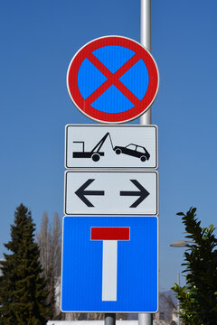 A vertical stack of road signs showing no parking and no stopping warnings above a tow away zone alert and a dead end street indicator against a clear blue sky.