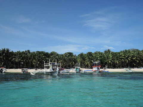 Tropical paradise with crystal clear water and traditional boats on the shore of Boracay Island, Philippines.
