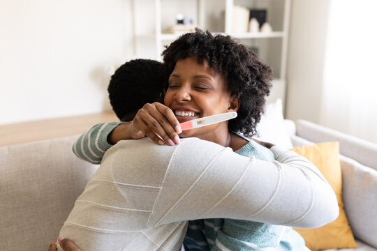 Happy couple embracing after positive pregnancy test result