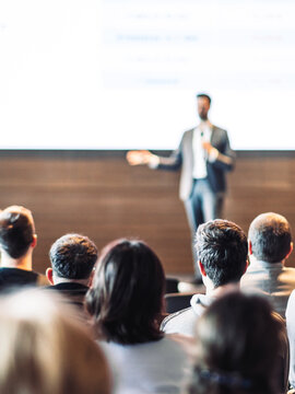 Speaker giving a talk in conference hall at business event. Rear view of unrecognizable people in audience at the conference hall. Business and entrepreneurship concept