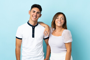 Fototapeta premium Young caucasian couple isolated on blue background happy and laughing