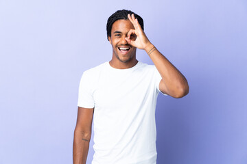 Naklejka premium Young African American man with braids man isolated on purple background showing ok sign with fingers