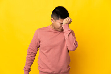 Young Ecuadorian man isolated on yellow background with headache