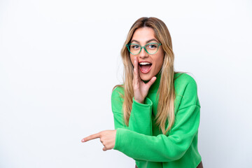 Young Uruguayan woman isolated on white background pointing to the side to present a product and whispering something