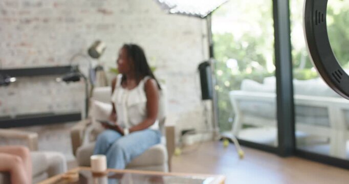 African American women recording interview, phone recording, checking tablet, sipping mug