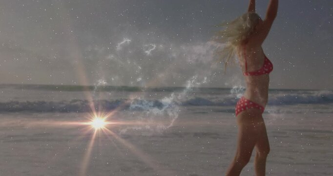 Vertical video: Entering surf, woman in red bikini splashing, turning to face sea flare, copy space