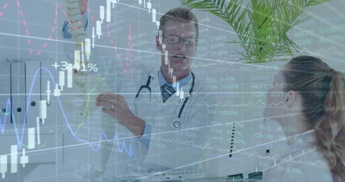 Dr lifting spine model, pointing spine and teaching medical trainee while finance charts overlaying