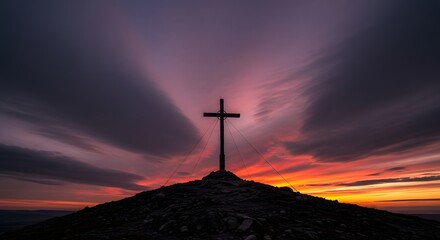 Obraz premium Silhouette of a cross on a hill against a dramatic sunset sky.