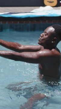 Vertical video: Reaching man in trunks catching beach ball as it enters left, playing in home pool