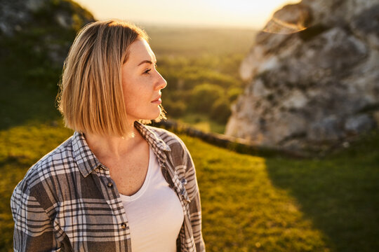 Young Woman Gazes Thoughtfully Into Distance During Golden Hour Outdoors in Nature