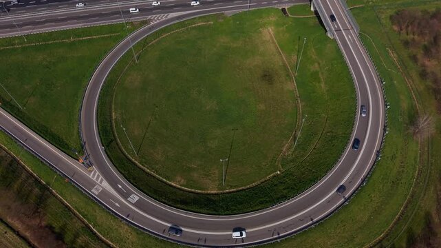 Highway Interchange from Above: An aerial view captures the intricate design of a highway interchange, with cars navigating the circular road surrounded by vibrant green grass.