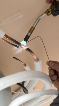 Professional hvac technician brazing copper pipes with a gas torch during the installation of a new air conditioning unit, ensuring a secure and leak proof connection for the refrigeration system