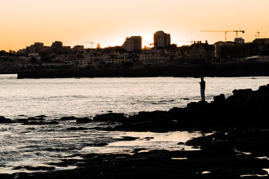 A man fishing in Praia Da Duquesa beach in Cascais, Portugal. 