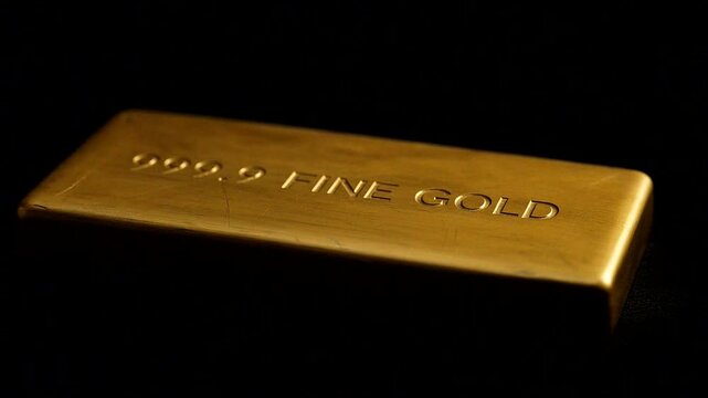 Gold bullion bar with high purity engraved, resting on a dark background, symbolizing wealth and investment.