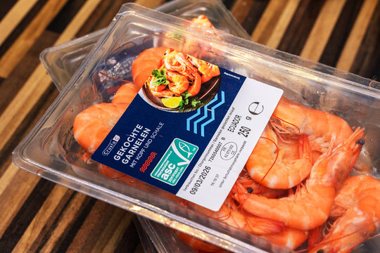 ISERLOHN, GERMANY - MARCH 8, 2026: A close-up of Crusta Nova "Gekochte Garnelen" (cooked prawns) in a 250g plastic package on a wooden surface, showing the ASC logo and origin from Ecuador.