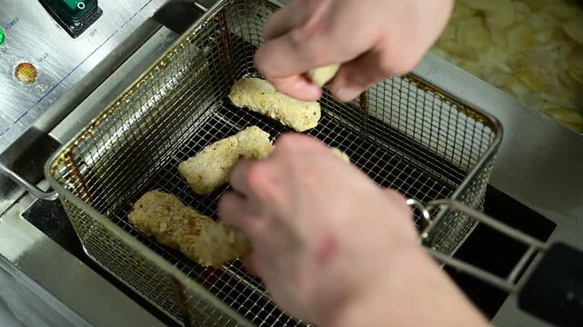 Chef deep frying croquettes and potato chips in a restaurant kitchen