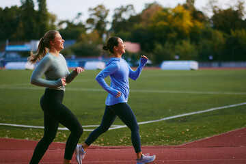 Two female athletes jogging together on outdoor running track