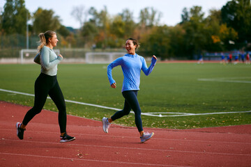 Obraz premium Female runners enjoying outdoor workout on stadium track