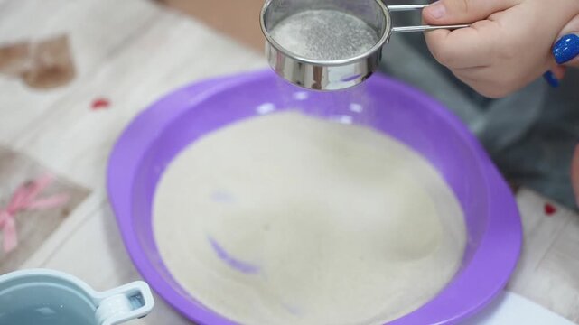 A child at a master class sifts sand through a sieve in close-up. High quality video