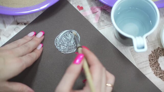 The child and the mother paint the paper with glue to fill the drawing with sand. Developing master class